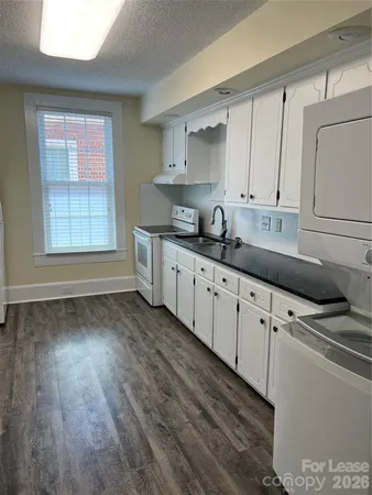 a kitchen with granite countertop a sink a stove and cabinets