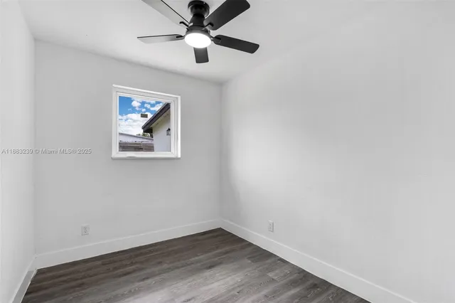 an empty room with wooden floor and ceiling fan