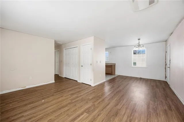 an empty room with wooden floor cabinet and windows
