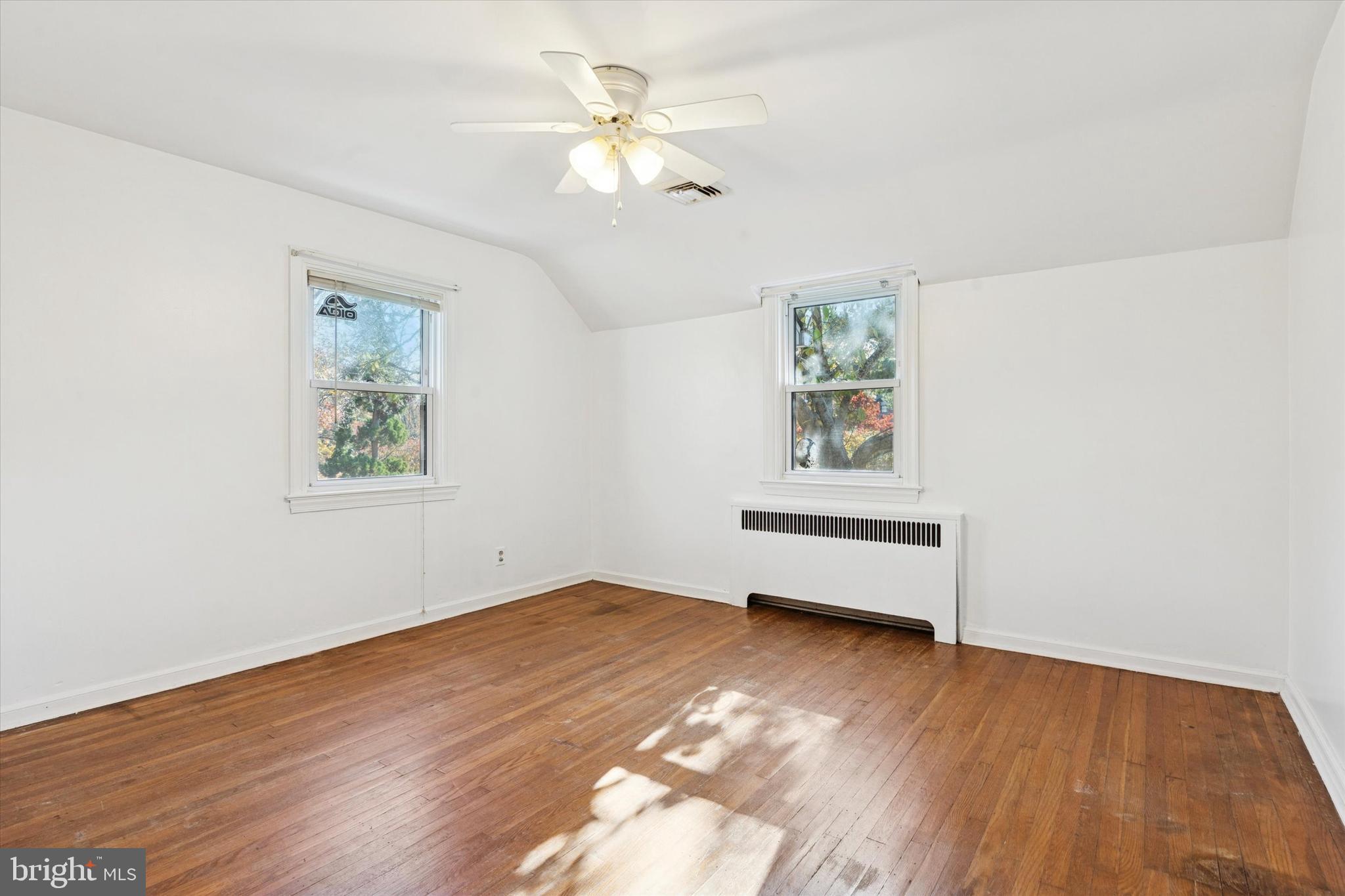 25 Green Valley Road Wallingford, PA 19086 - Photo 34 of 63 an empty room with wooden floor chandelier fan and windows