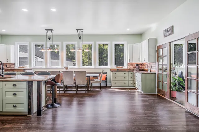 a room with stainless steel appliances kitchen island granite countertop wooden floor and a view of living room