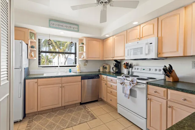 a kitchen with granite countertop white cabinets and white appliances