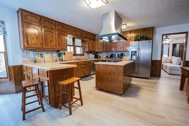 a kitchen with stainless steel appliances granite countertop a table chairs and a refrigerator
