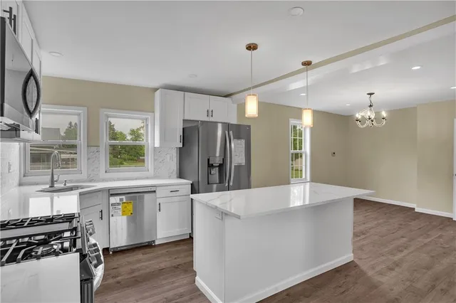 a large kitchen with kitchen island a stove a refrigerator a sink a dining table and chairs with wooden floor