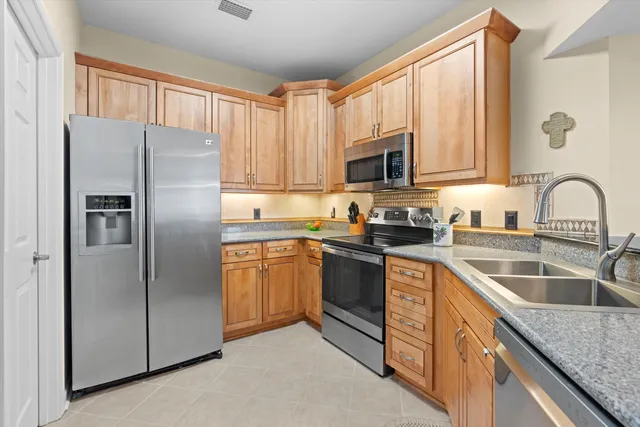a kitchen with granite countertop stainless steel appliances a refrigerator sink and microwave
