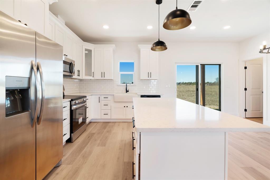 213 Private Road Sumner, TX 75486 - Photo 9 of 19 a large kitchen with stainless steel appliances kitchen island granite countertop a refrigerator a stove and a sink with wooden floor