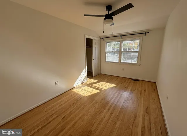 a view of empty room with wooden floor and fan