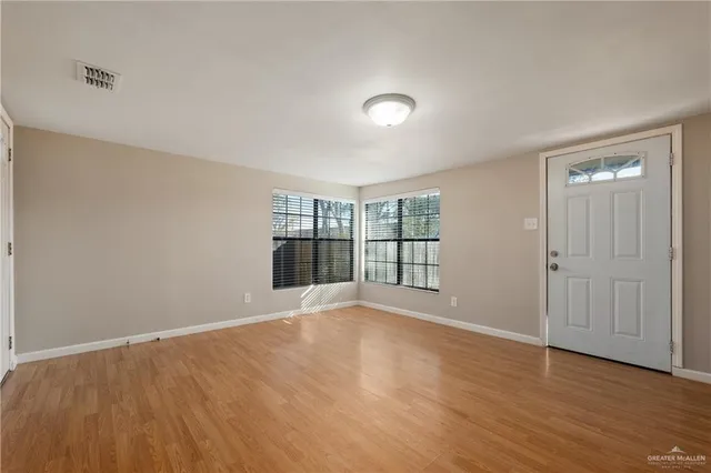 a view of an empty room with wooden floor and a window