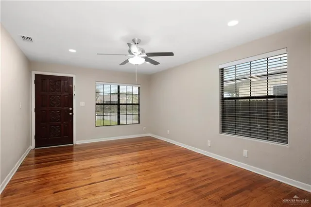 a view of an empty room with wooden floor and a window