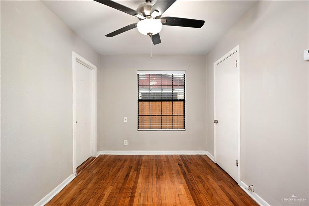 309 South 4th Street McAllen, TX 78501 - Photo 5 of 21 an empty room with wooden floor chandelier fan and windows