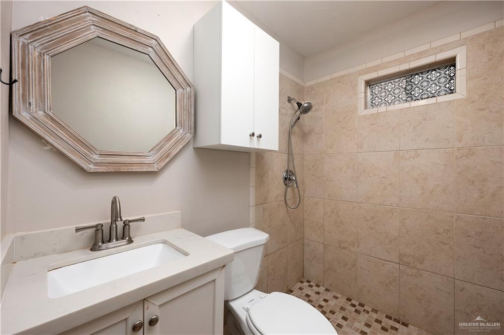 309 South 4th Street McAllen, TX 78501 - Photo 8 of 21 a bathroom with a toilet a sink and mirror