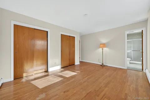 a view of an empty room with wooden floor and closet