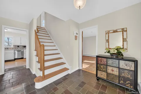a view of a hallway to a livingroom with wooden floor and furniture