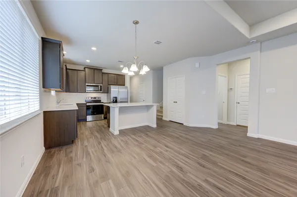 a large kitchen with a center island wooden floor stainless steel appliances and a window
