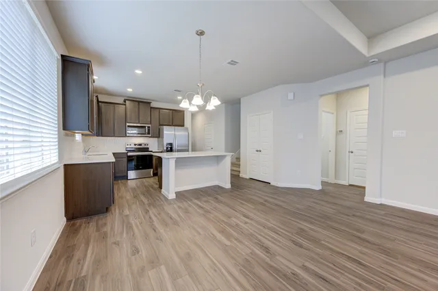 a large kitchen with a center island wooden floor stainless steel appliances and a window