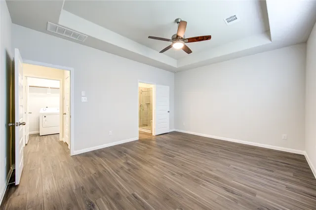 an empty room with wooden floor ceiling fan and windows
