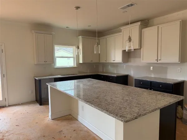 a kitchen with kitchen island granite countertop a sink a counter top space and cabinets