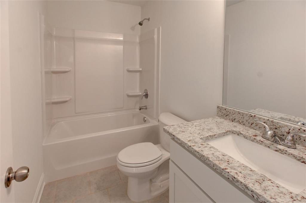 41 Woodland Road Covington, GA 30016 - Photo 34 of 35 a bathroom with a granite countertop sink a toilet and bathtub