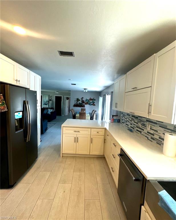 1263 North Collier Boulevard Marco Island, FL 34145 - Photo 4 of 4 Kitchen featuring a peninsula, fridge with ice dispenser, dishwasher, white cabinetry, and open floor plan