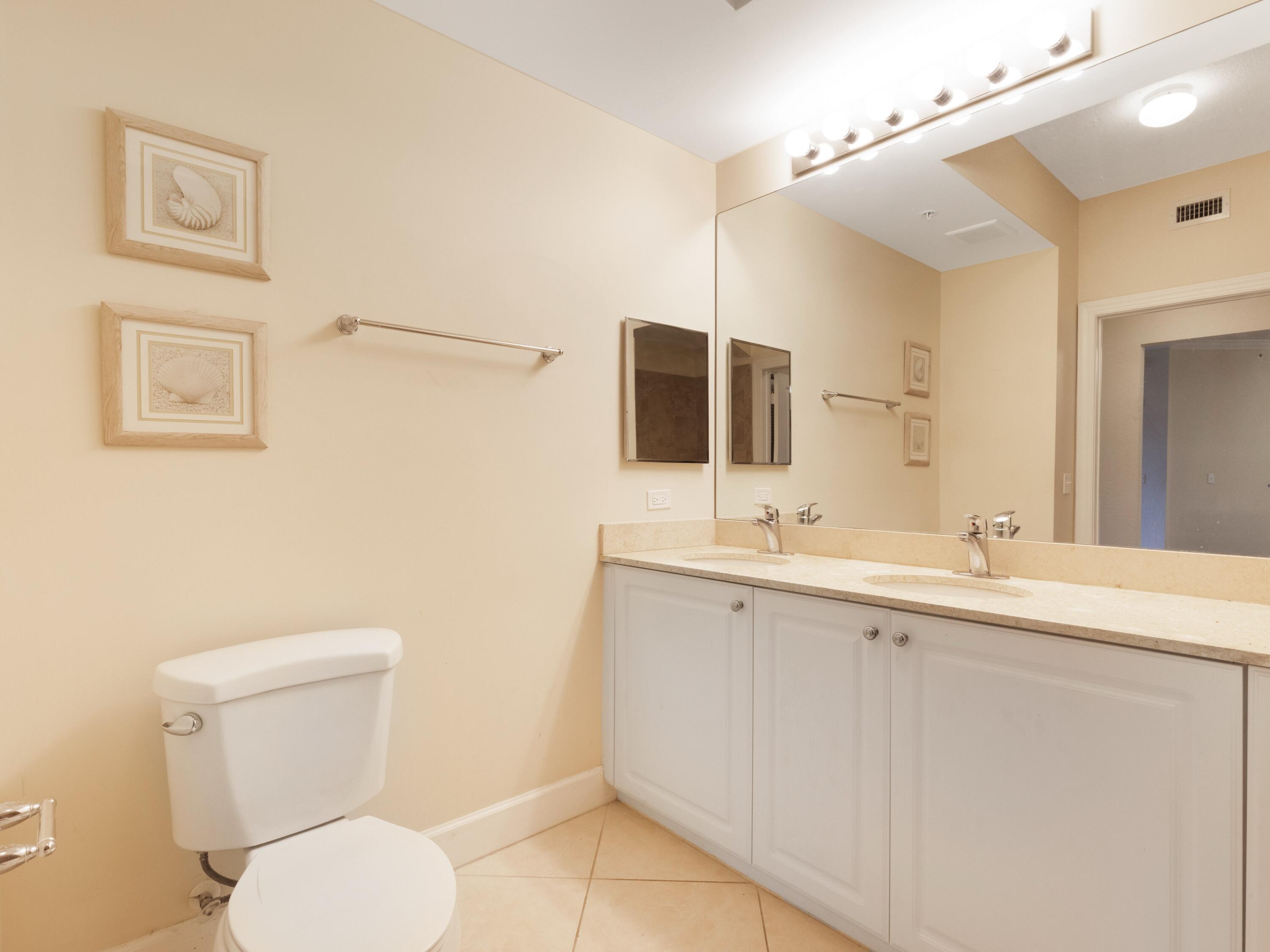1690 Renaissance Commons Boulevard, Unit 1412 Boynton Beach, FL 33426 - Photo 16 of 49 a bathroom with a toilet sink and mirror