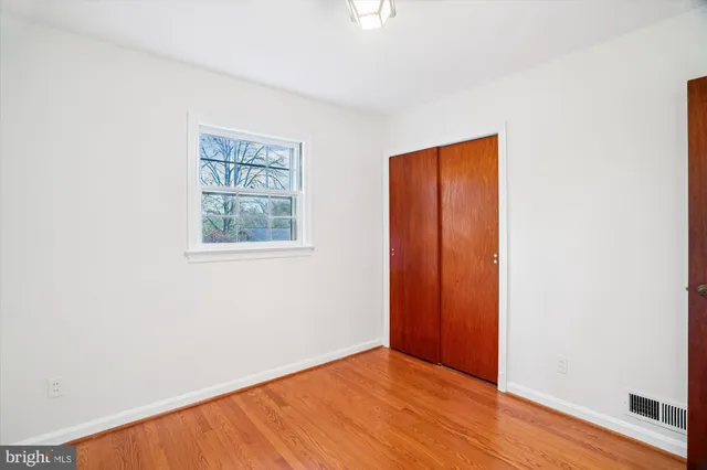 an empty room with wooden floor and window