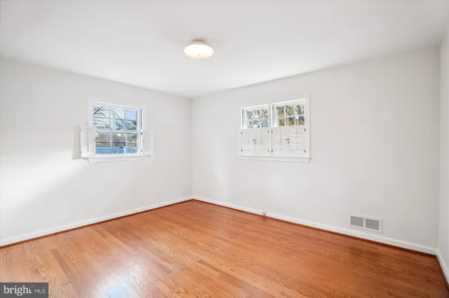 a view of an empty room with wooden floor and closet
