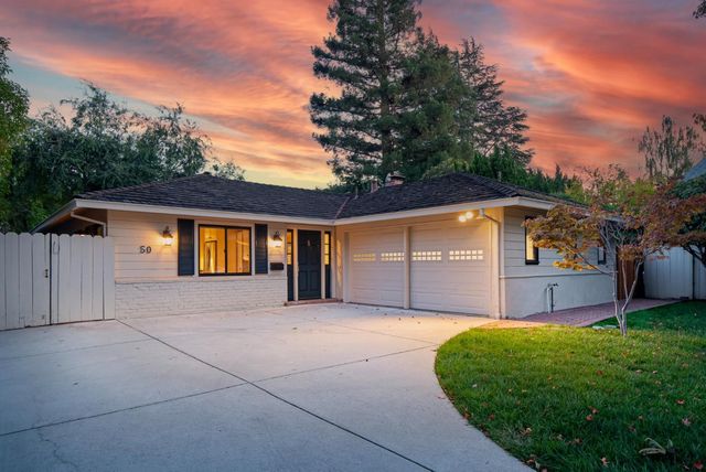a front view of house with yard and trees in the background