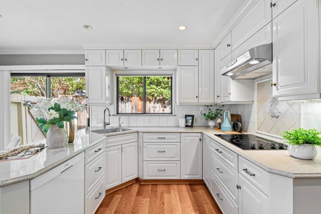 a kitchen with white cabinets a window and white appliances