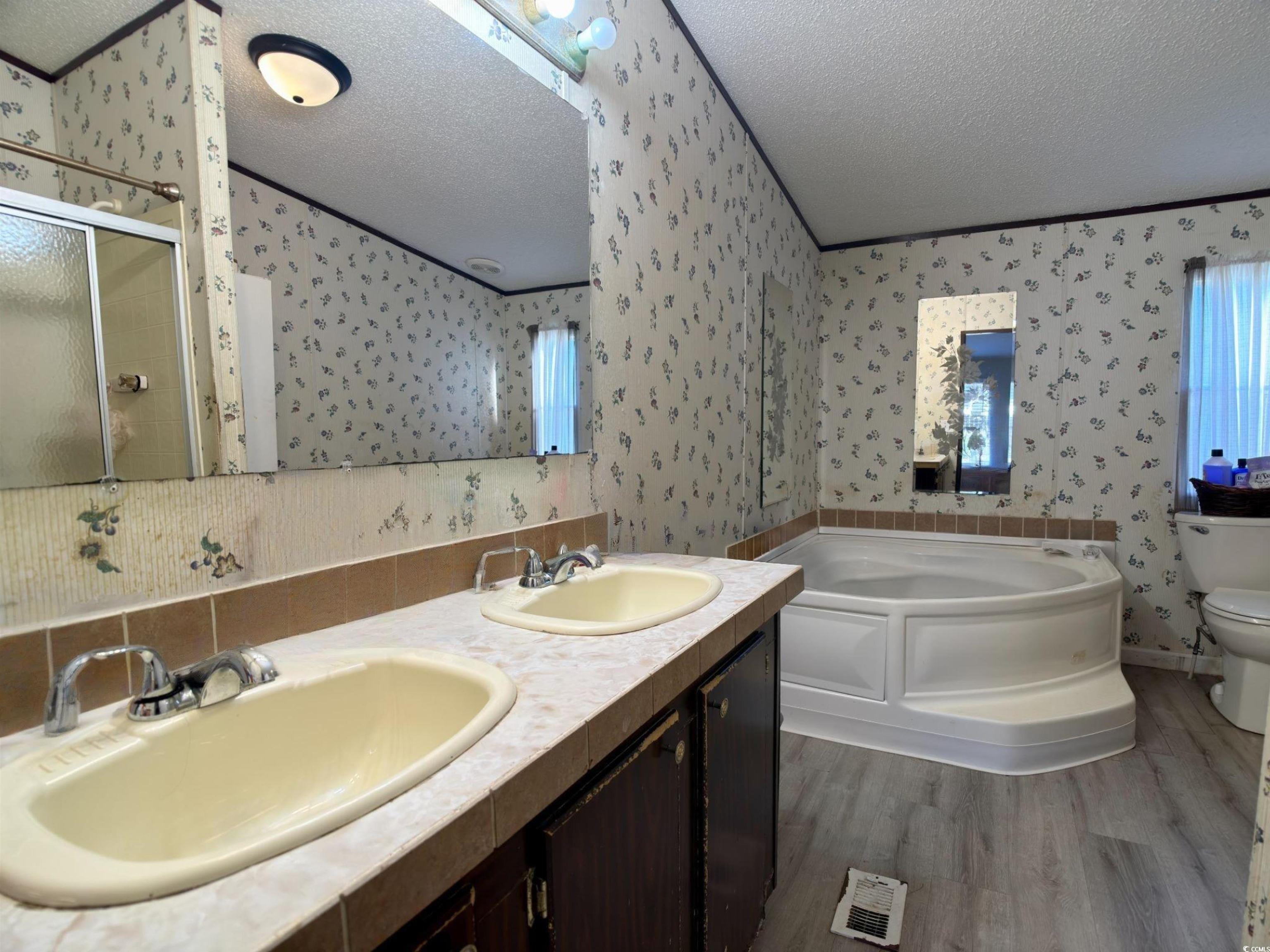 119 Ranchette Circle Myrtle Beach, SC 29588 - Photo 13 of 27 Full bathroom with a textured ceiling, a bath, double vanity, dark wood-style flooring, and a shower stall