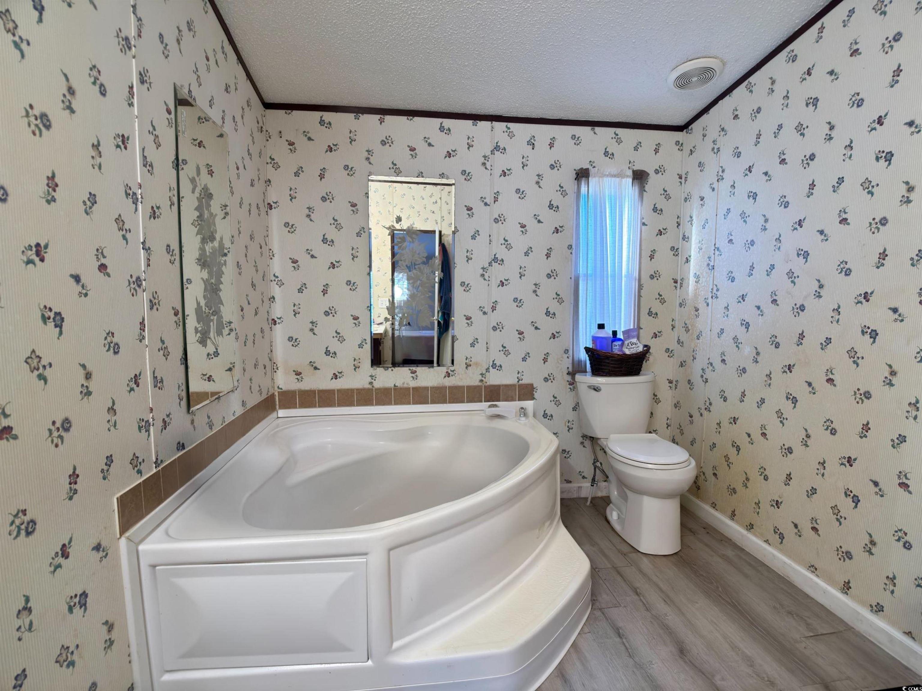 119 Ranchette Circle Myrtle Beach, SC 29588 - Photo 14 of 27 Full bathroom featuring a bath, a textured ceiling, light wood finished floors, wallpapered walls, and crown molding
