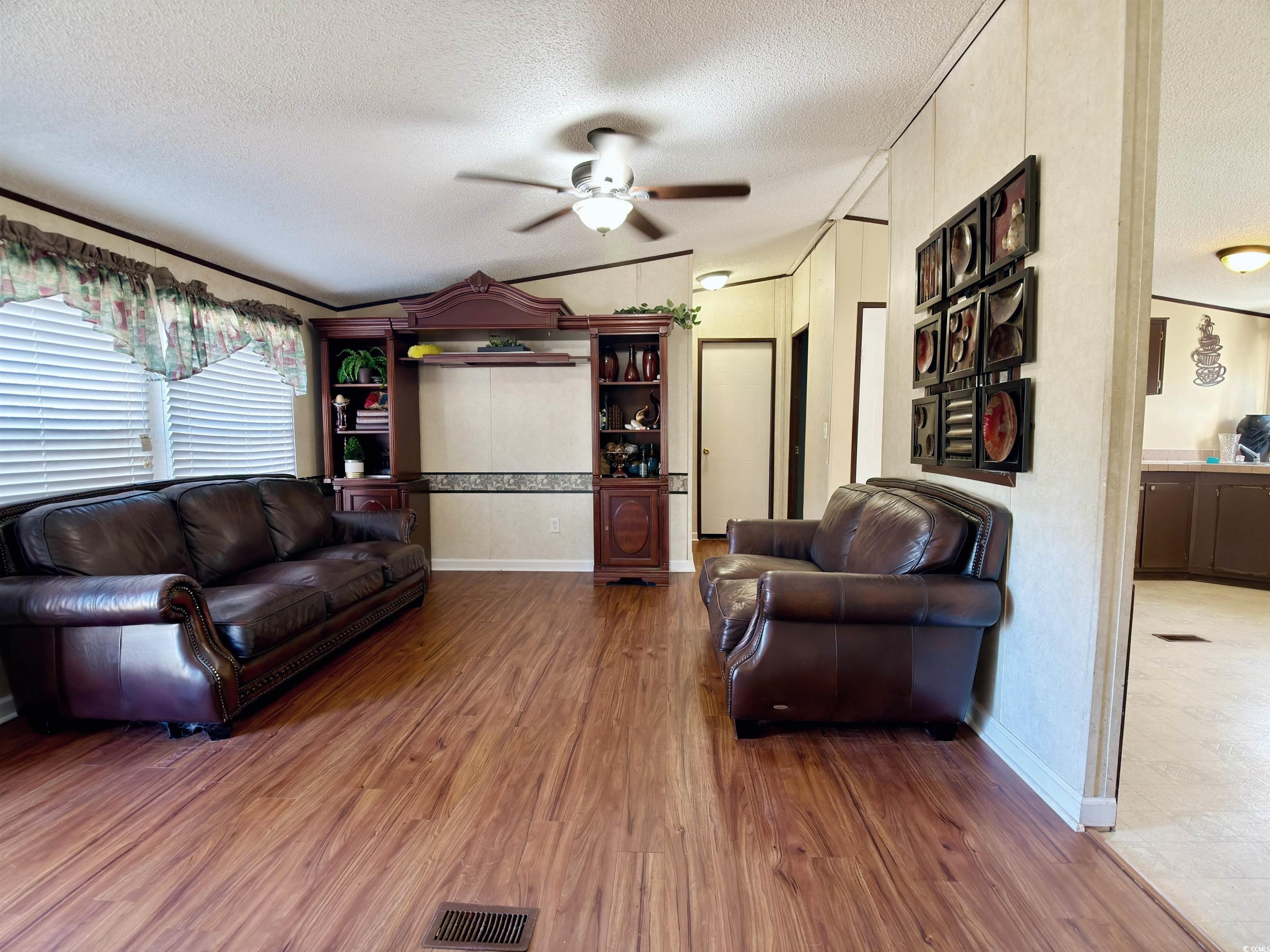 119 Ranchette Circle Myrtle Beach, SC 29588 - Photo 5 of 27 Living room with vaulted ceiling, a textured ceiling, wood finished floors, and a ceiling fan
