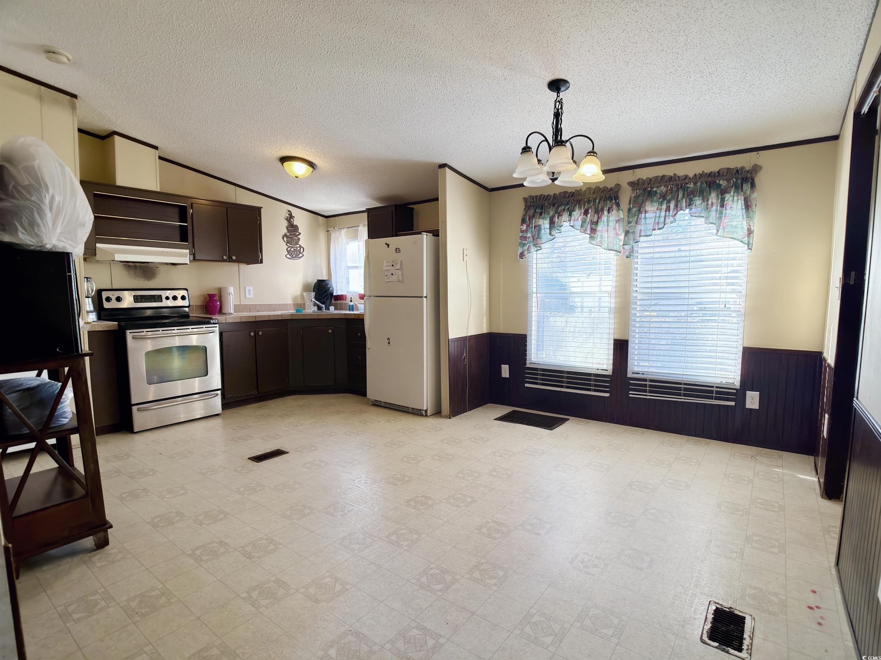119 Ranchette Circle Myrtle Beach, SC 29588 - Photo 8 of 27 Kitchen featuring wainscoting, stainless steel electric range oven, light floors, freestanding refrigerator, and a textured ceiling