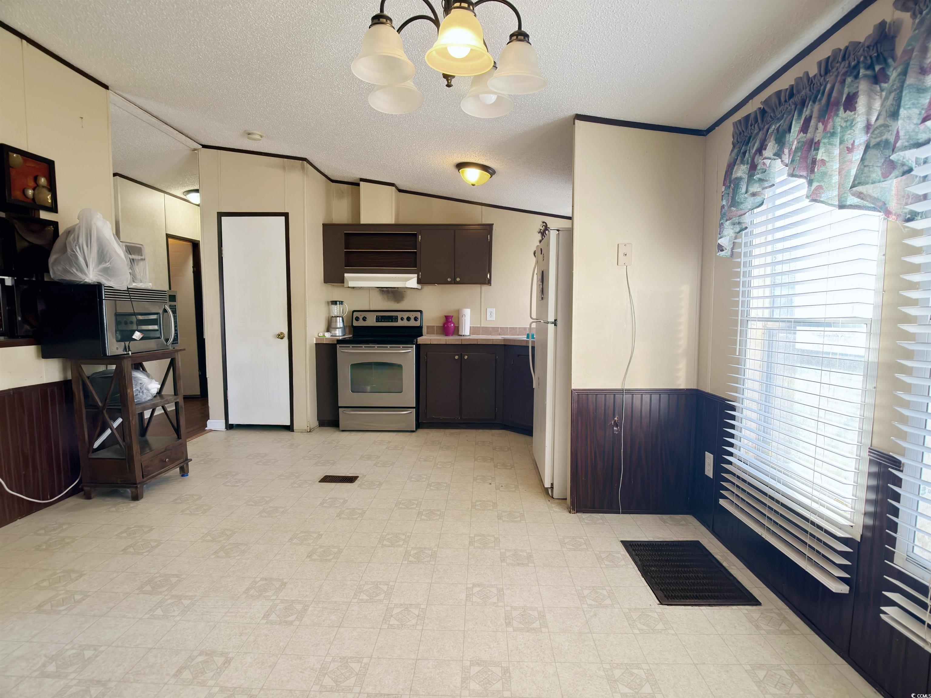 119 Ranchette Circle Myrtle Beach, SC 29588 - Photo 9 of 27 Kitchen with wainscoting, wooden walls, lofted ceiling, a chandelier, and stainless steel appliances