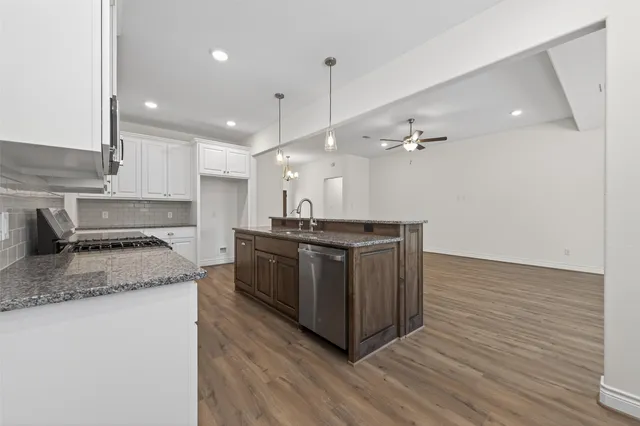a kitchen with stainless steel appliances granite countertop a sink a stove and a wooden floors