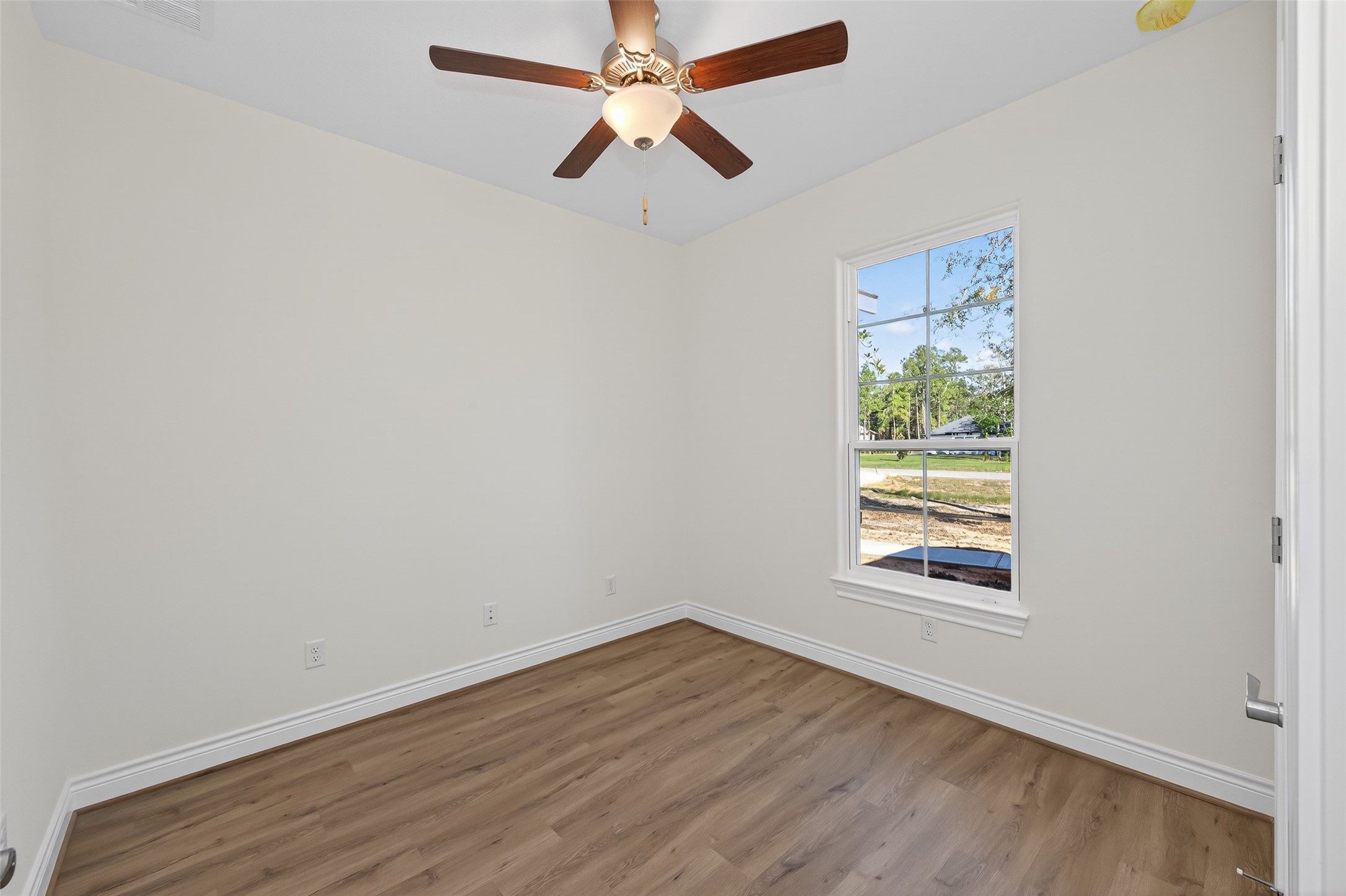 12879 Oak Barrel Road Willis, TX 77378 - Photo 24 of 37 an empty room with wooden floor chandelier fan and windows