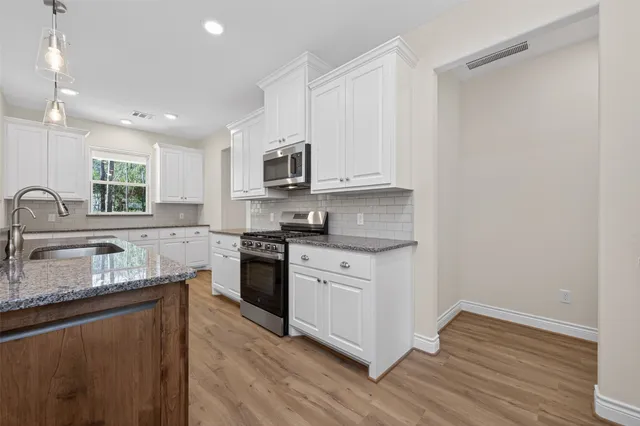 a kitchen with kitchen island granite countertop a sink cabinets and wooden floor