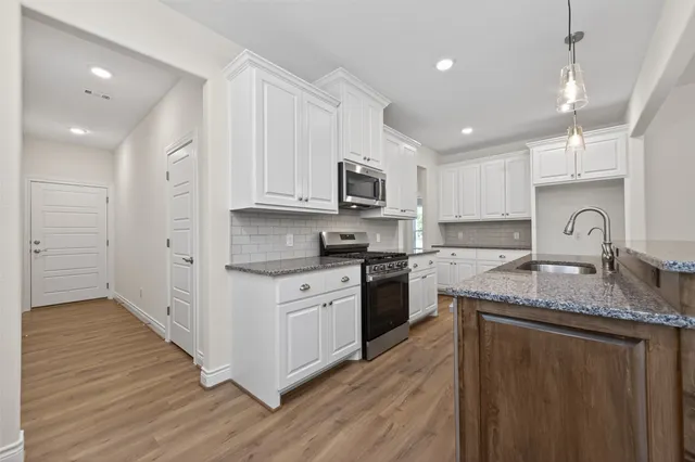 a kitchen with stainless steel appliances granite countertop a sink stove cabinets and wooden floor