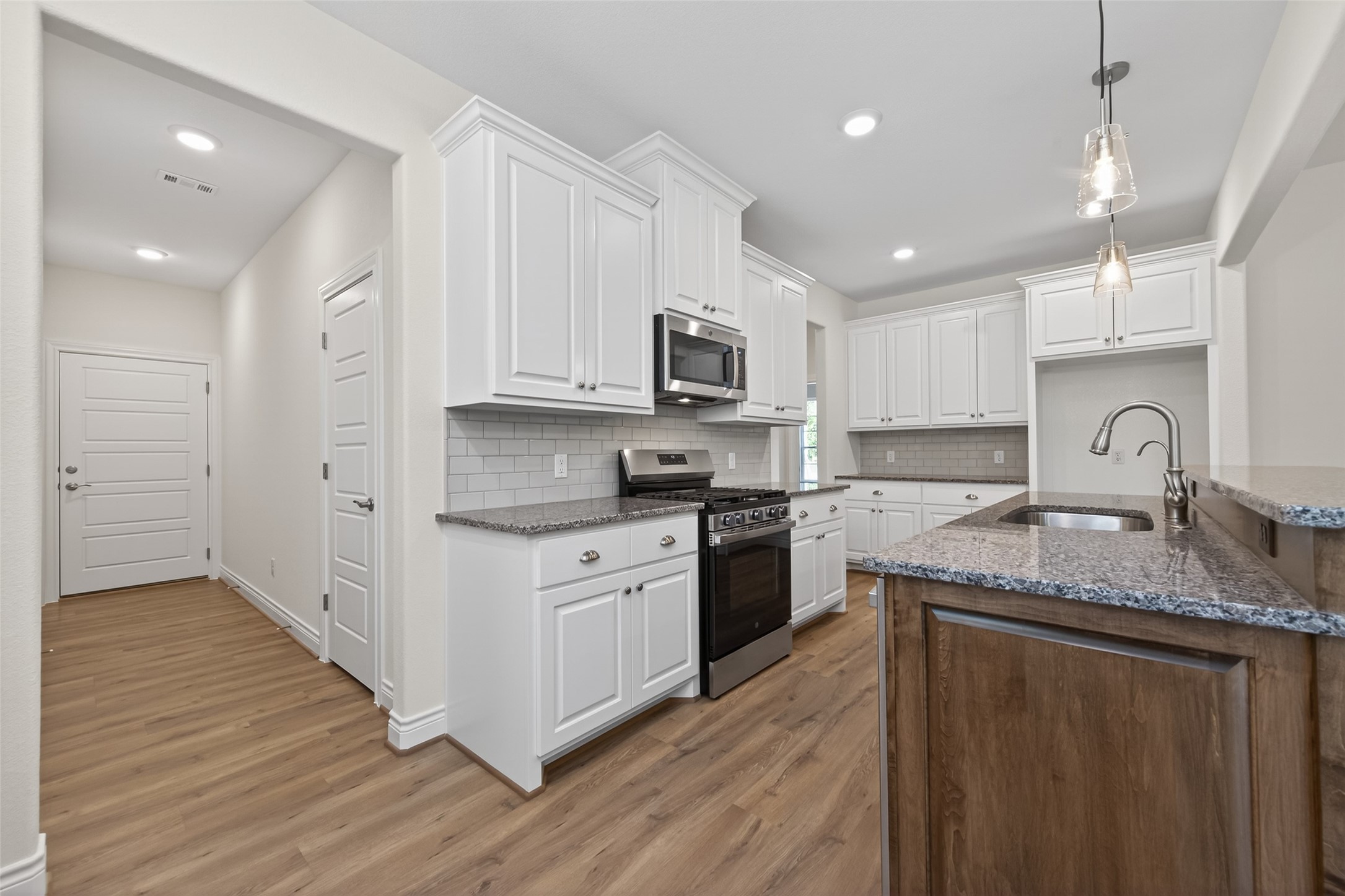 12879 Oak Barrel Road Willis, TX 77378 - Photo 10 of 37 a kitchen with stainless steel appliances granite countertop a sink stove cabinets and wooden floor