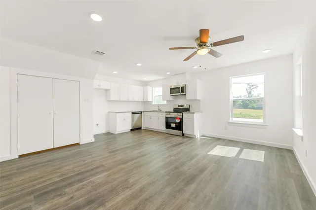 a view of a kitchen with wooden floor and a ceiling fan