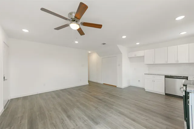 a view of an empty room with a window and wooden floor