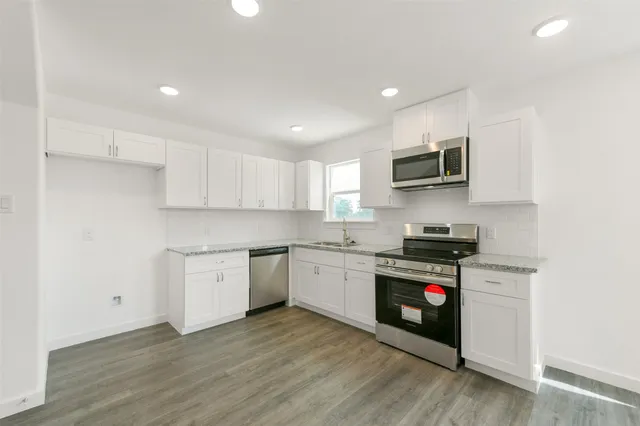 a kitchen with granite countertop a stove top oven a sink dishwasher and a microwave oven on the wooden floor