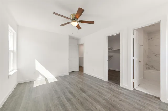 an empty room with wooden floor fan and windows