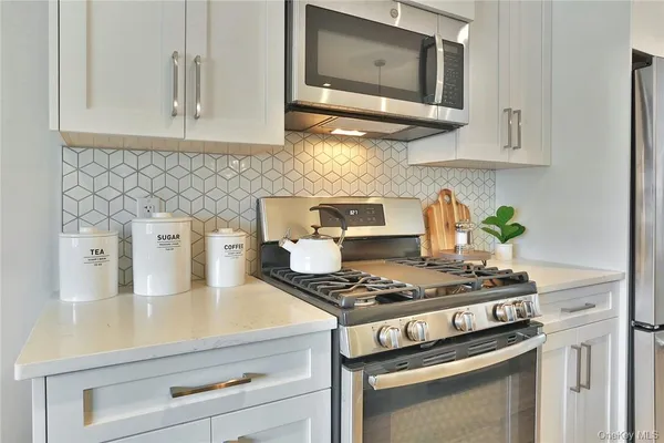 a kitchen with stainless steel appliances granite countertop a stove and a white cabinets
