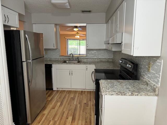 6014 Indrio Road, Unit F2 Fort Pierce, FL 34951 - Photo 3 of 27 a kitchen with a sink a refrigerator a window and cabinets
