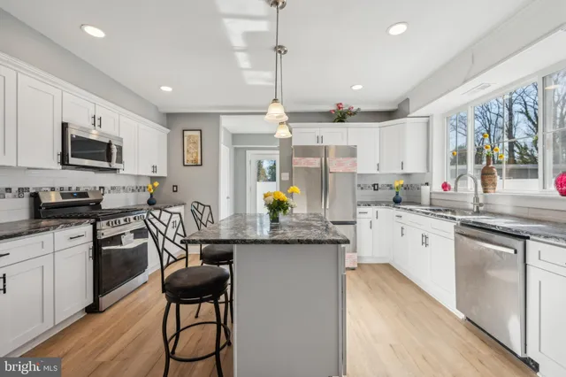 a kitchen with stainless steel appliances granite countertop a stove top oven a sink dishwasher a dining table and chairs with wooden floor