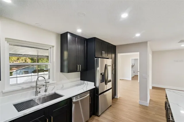 a large kitchen with a center island wooden floor and stainless steel appliances