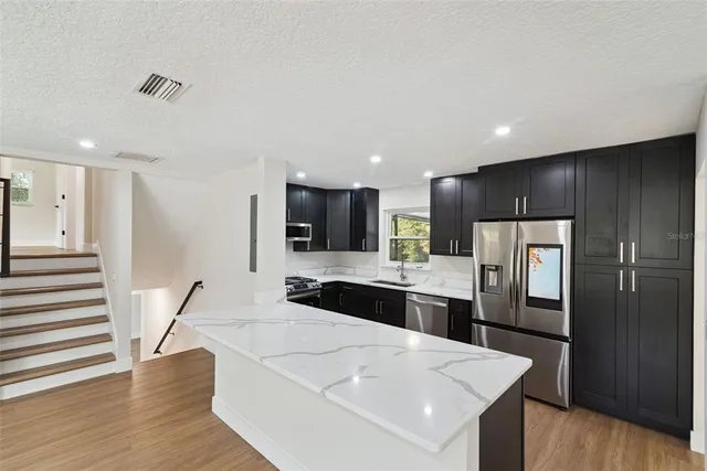 a living room with stainless steel appliances kitchen island granite countertop a stove and a refrigerator