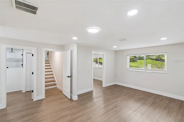 a view of an empty room with wooden floor and a window