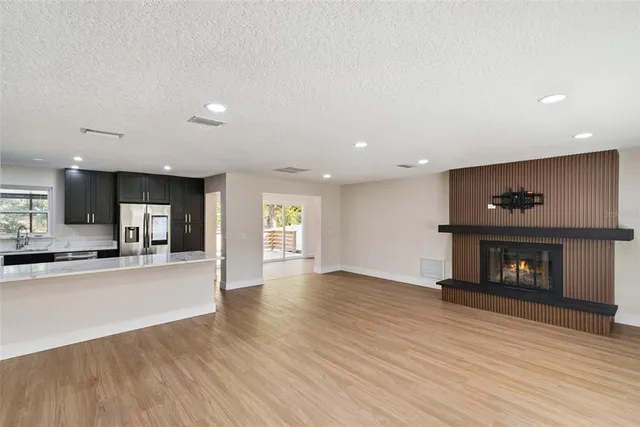 an empty room with wooden floor a fireplace and windows