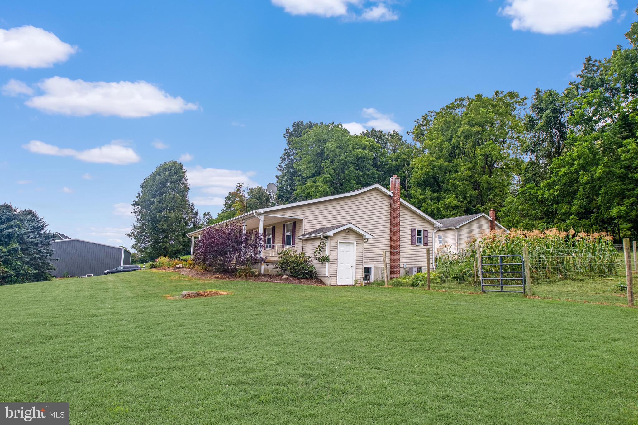 129 Walker Drive Spring Mills, PA 16875 - Photo 22 of 29 a view of a white house in front of a big yard with plants and large trees